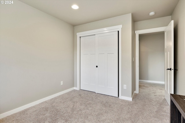 unfurnished bedroom featuring light carpet and a closet