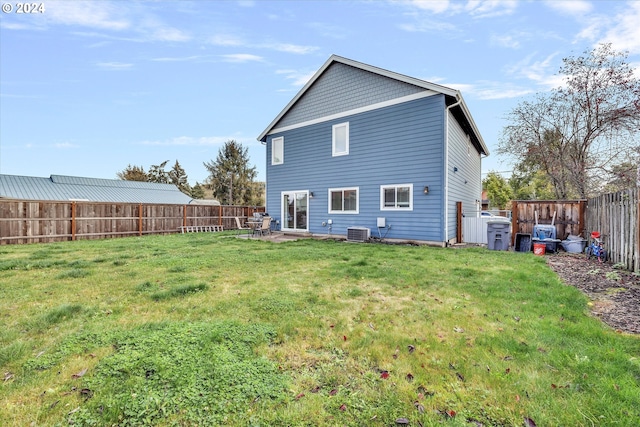 back of property with central air condition unit and a yard