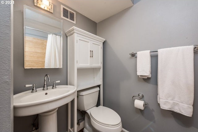 bathroom featuring toilet, a shower with curtain, and sink