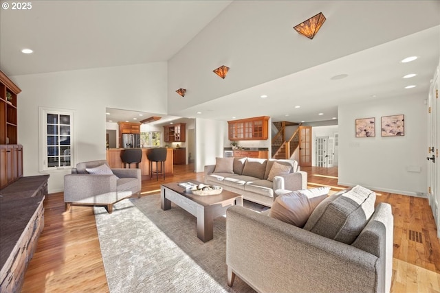 living room with high vaulted ceiling and light hardwood / wood-style floors