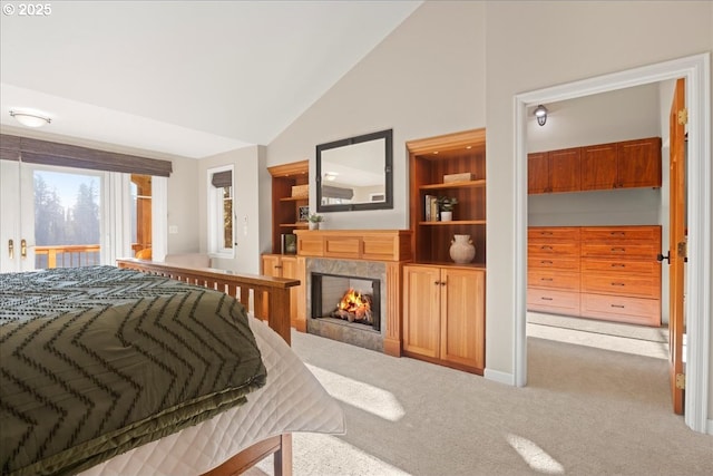 bedroom with lofted ceiling, a premium fireplace, light carpet, and access to outside