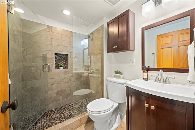 bathroom with vanity, a shower with shower door, and toilet