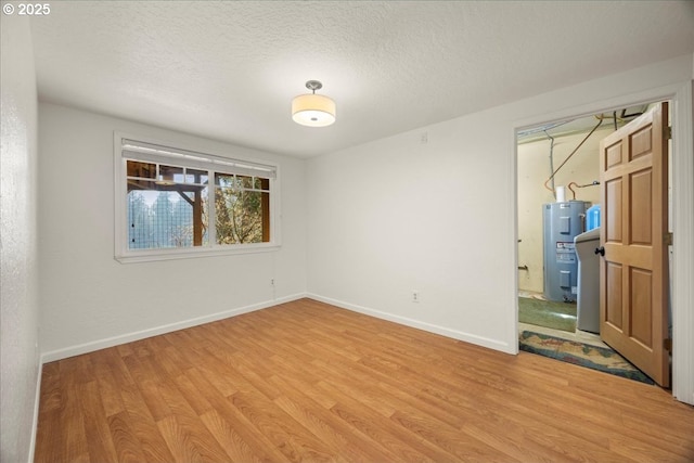 unfurnished room featuring electric water heater, a textured ceiling, and light hardwood / wood-style flooring