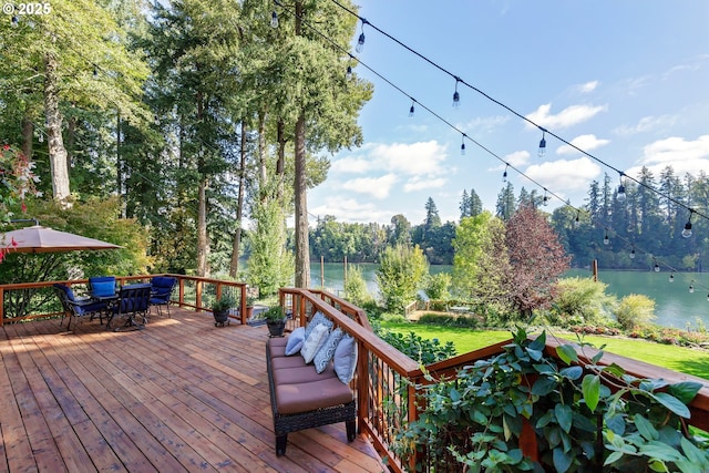 wooden deck featuring a water view and a lawn