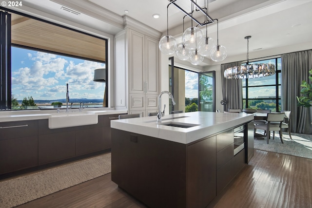 kitchen featuring pendant lighting, a kitchen island with sink, sink, an inviting chandelier, and dark hardwood / wood-style flooring