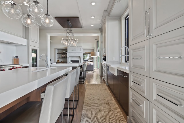 kitchen featuring dark wood-type flooring, a breakfast bar, sink, and white cabinetry