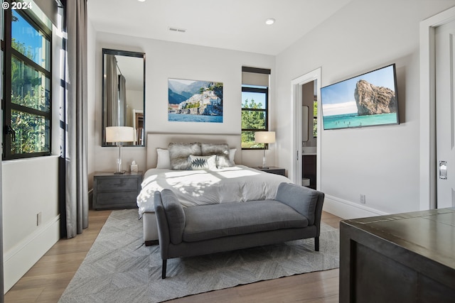 bedroom with light hardwood / wood-style flooring and ensuite bathroom