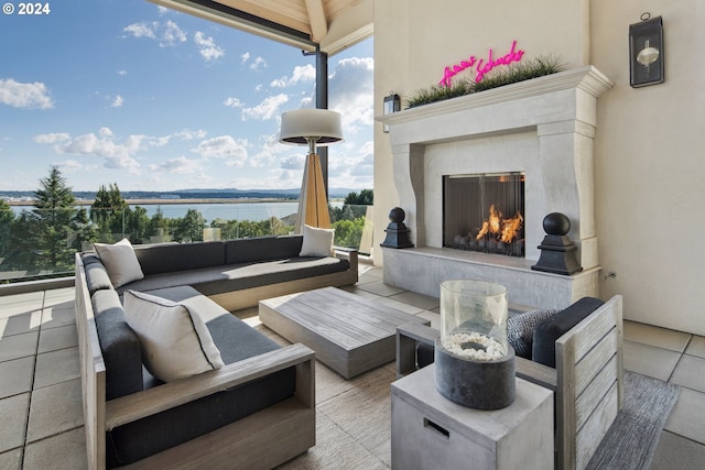 view of patio with an outdoor living space with a fireplace and a water view