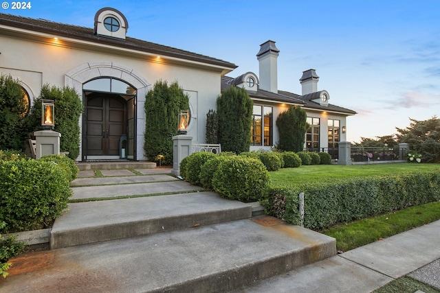 exterior entry at dusk featuring a lawn