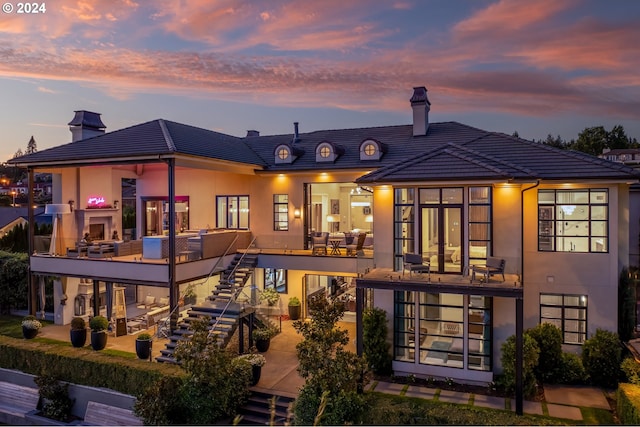 back house at dusk with a balcony and a patio