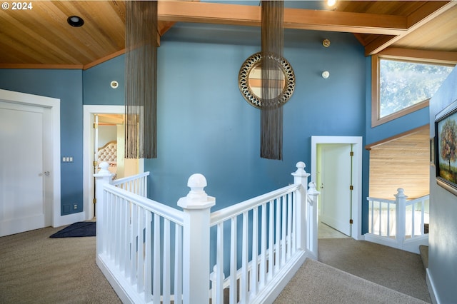 hall with carpet flooring, wood ceiling, and vaulted ceiling