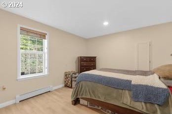 bedroom featuring a baseboard heating unit and light wood-type flooring