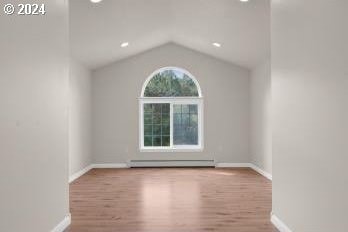 unfurnished room with light hardwood / wood-style flooring, a baseboard heating unit, and lofted ceiling