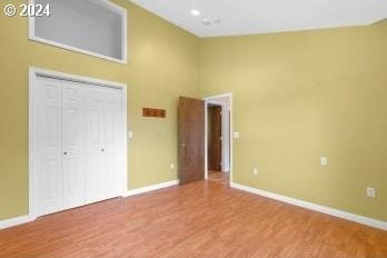 unfurnished bedroom featuring high vaulted ceiling and wood-type flooring