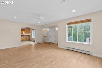 unfurnished living room with ceiling fan, a baseboard radiator, and light wood-type flooring