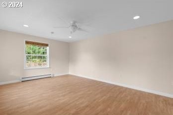 empty room featuring baseboard heating, light wood-type flooring, and ceiling fan