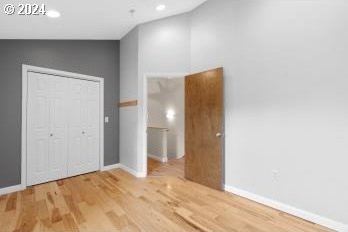 unfurnished bedroom with a closet, hardwood / wood-style floors, and vaulted ceiling