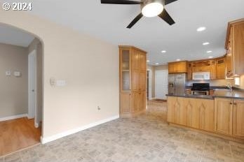 kitchen featuring ceiling fan, black gas range oven, and stainless steel refrigerator with ice dispenser