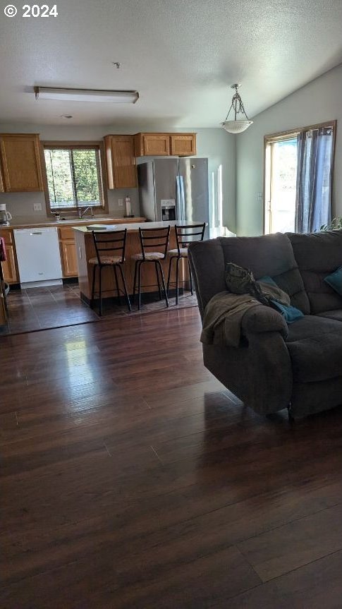 living room featuring dark wood-type flooring, a wealth of natural light, a textured ceiling, and lofted ceiling