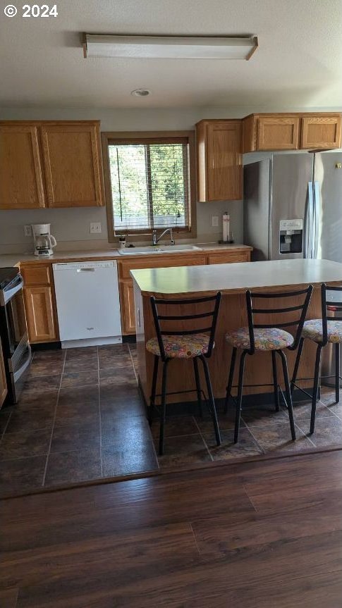 kitchen with dark hardwood / wood-style flooring, appliances with stainless steel finishes, sink, and a breakfast bar