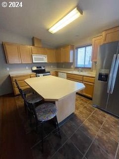 kitchen with stainless steel appliances, light brown cabinetry, a breakfast bar area, and a kitchen island