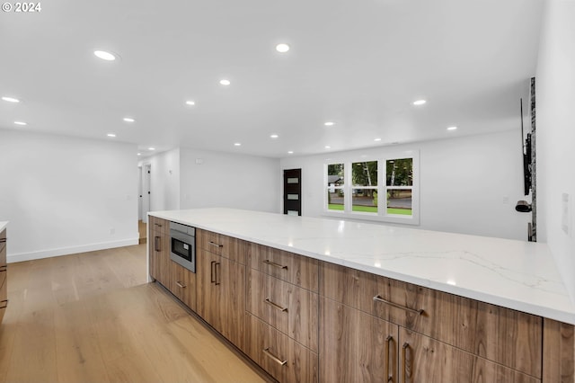 kitchen featuring light stone countertops, oven, and light hardwood / wood-style floors