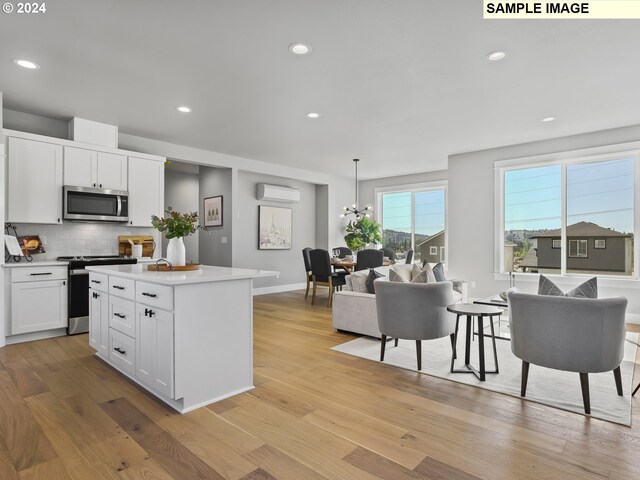 kitchen with appliances with stainless steel finishes, light hardwood / wood-style flooring, pendant lighting, and white cabinets