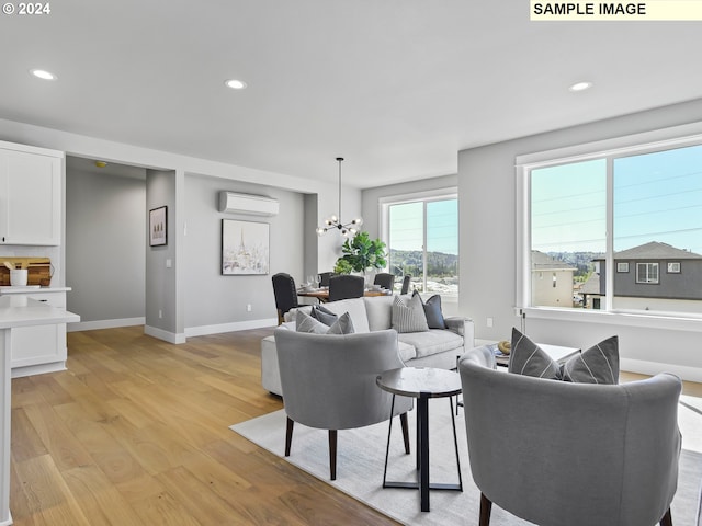 living room featuring a chandelier, a wall mounted air conditioner, and light wood-type flooring