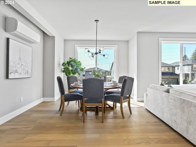 dining area featuring light hardwood / wood-style floors, an inviting chandelier, and a wall mounted air conditioner