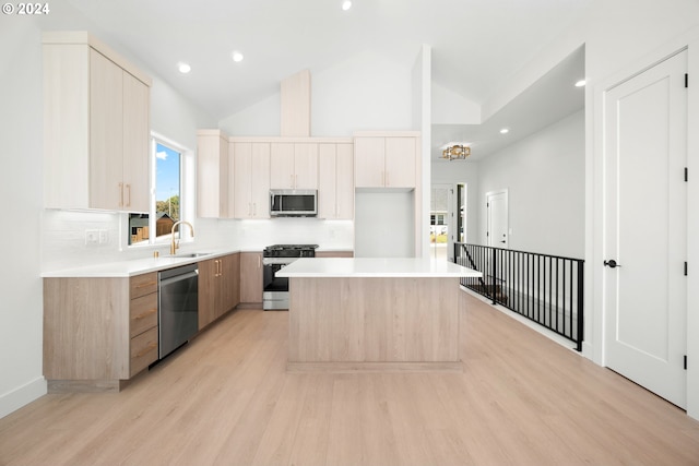 kitchen with sink, stainless steel appliances, light hardwood / wood-style flooring, backsplash, and a kitchen island