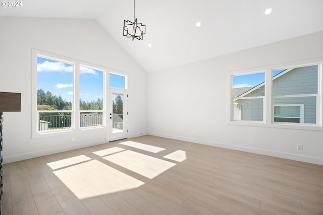 interior space featuring a notable chandelier, light wood-type flooring, and high vaulted ceiling