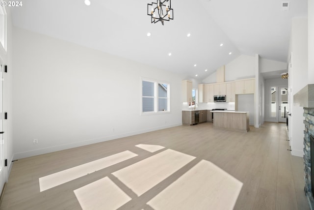 unfurnished living room featuring a wealth of natural light, light wood-type flooring, high vaulted ceiling, and french doors