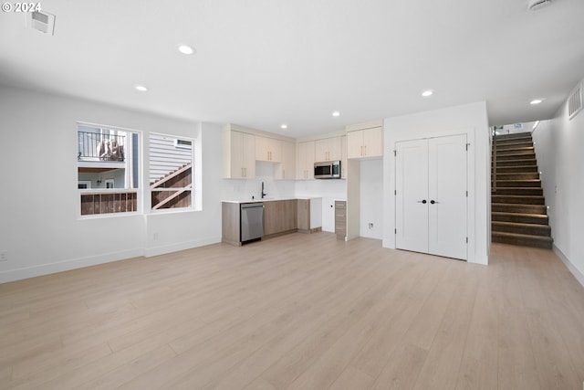 unfurnished living room featuring sink and light wood-type flooring