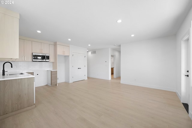 kitchen featuring backsplash, light wood-type flooring, and sink