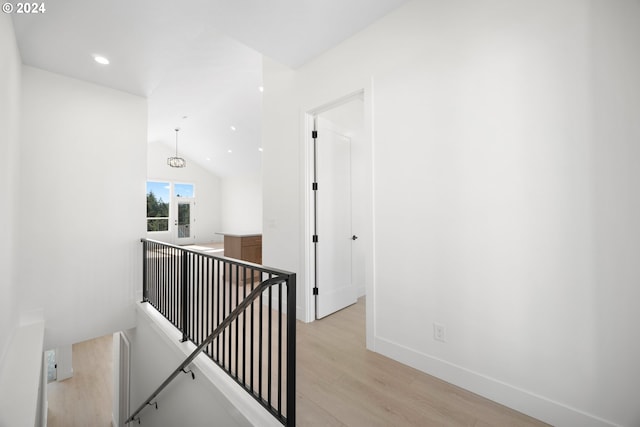 hallway with light hardwood / wood-style floors and lofted ceiling