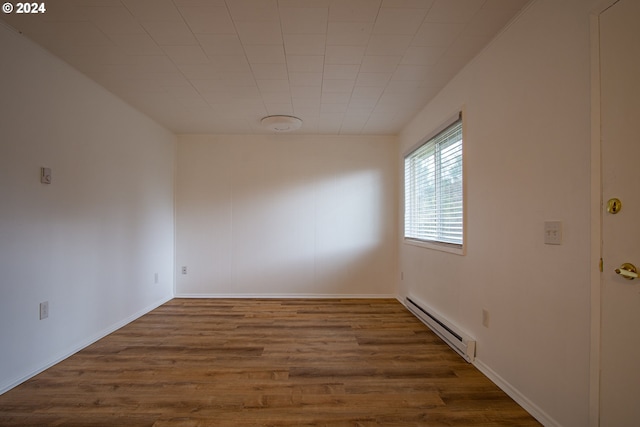 unfurnished room with wood finished floors and baseboard heating