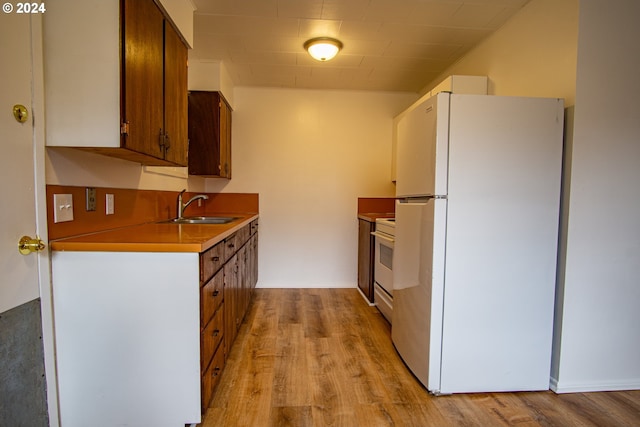 kitchen featuring white appliances, light countertops, light wood-style flooring, and a sink