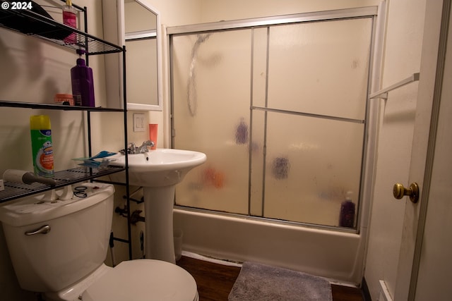 bathroom with hardwood / wood-style floors, bath / shower combo with glass door, and toilet