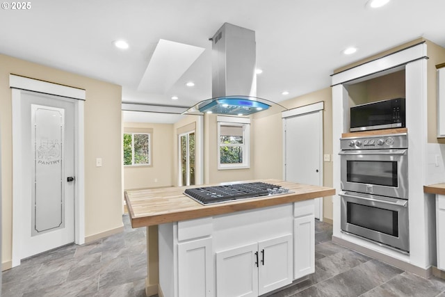 kitchen featuring recessed lighting, white cabinets, wooden counters, appliances with stainless steel finishes, and island exhaust hood