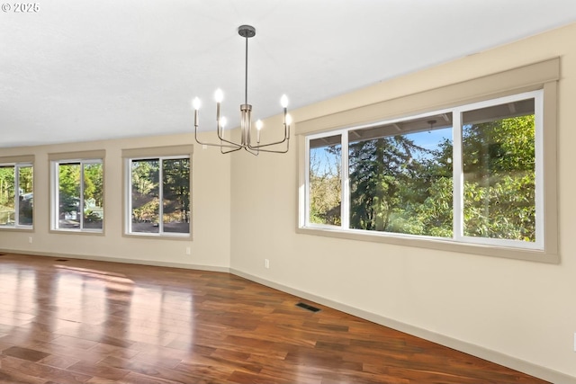 spare room featuring baseboards, visible vents, an inviting chandelier, and wood finished floors