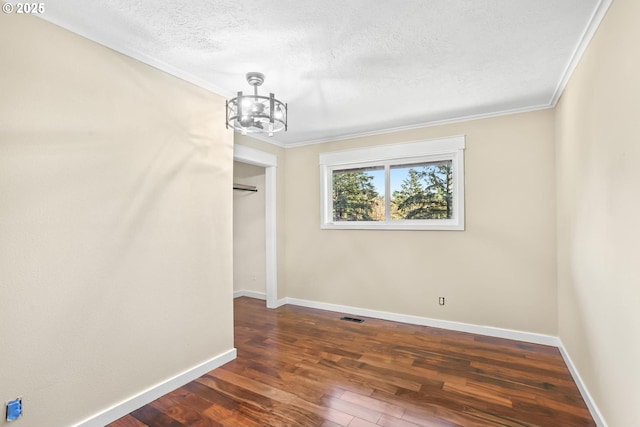 unfurnished dining area with a textured ceiling, baseboards, dark wood-type flooring, and ornamental molding