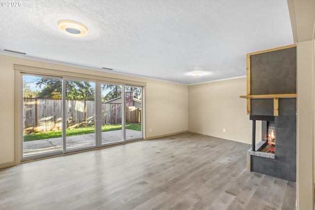 unfurnished living room featuring a textured ceiling, crown molding, wood finished floors, and a multi sided fireplace