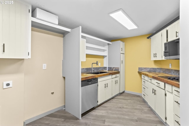 kitchen with open shelves, appliances with stainless steel finishes, a sink, and light wood-style floors