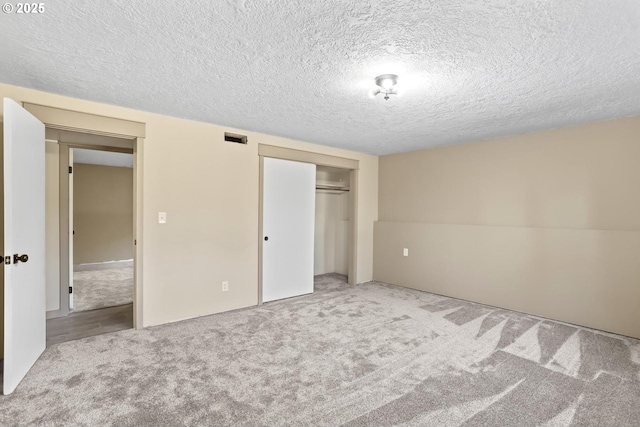 unfurnished bedroom with carpet, a textured ceiling, visible vents, and a closet