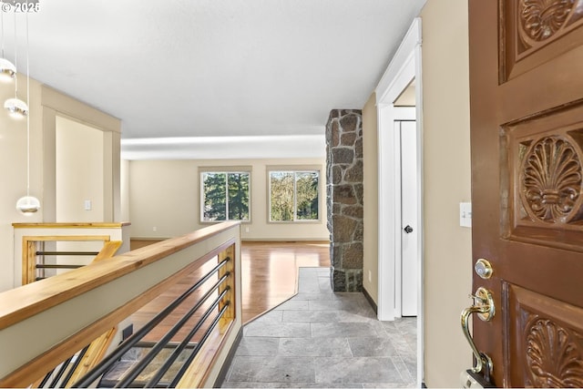 corridor featuring baseboards, an upstairs landing, and wood finished floors