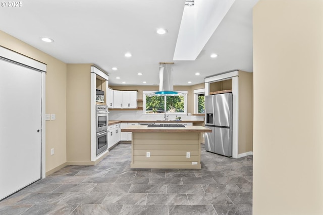 kitchen with stainless steel fridge, butcher block countertops, a center island, island exhaust hood, and open shelves