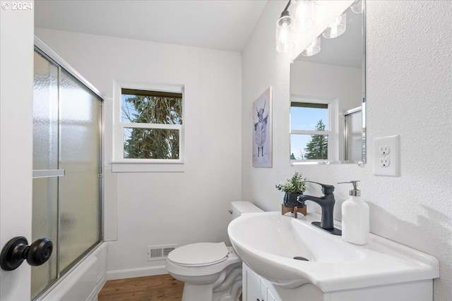 full bathroom with toilet, wood-type flooring, shower / bath combination with glass door, and vanity