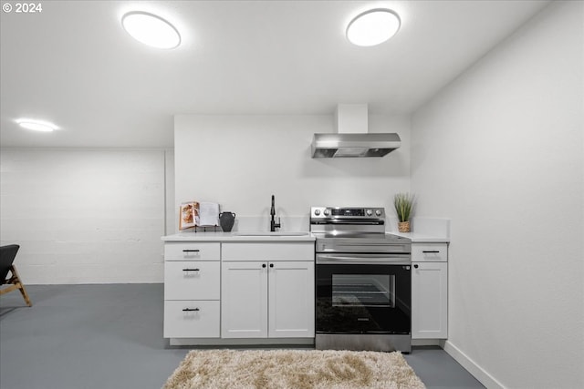 kitchen featuring stainless steel electric range, sink, wall chimney exhaust hood, concrete floors, and white cabinetry