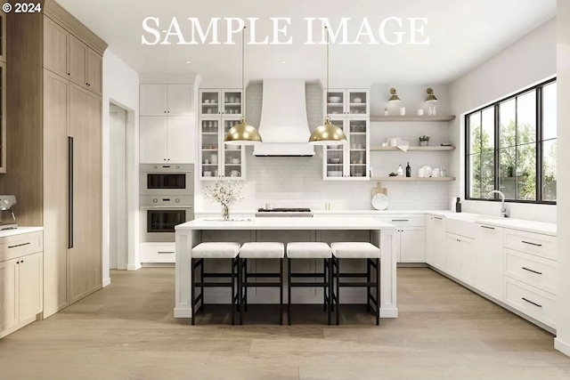 3744 NW Goldfinch Dr, Corvallis, OR 97330 - kitchen featuring light wood-style floors, backsplash, a breakfast bar area, and premium range hood
