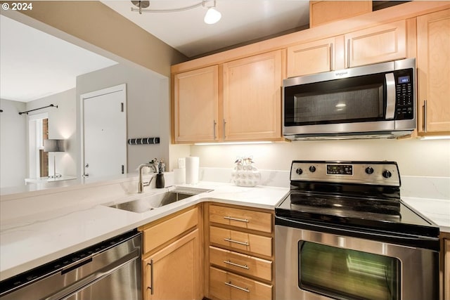 kitchen with light brown cabinets, stainless steel appliances, sink, and light stone counters